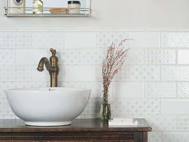 white bathroom ideas - textured metro tiles behind a stand-alone basin with brass tap 