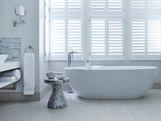 white freestanding bath with white shutters and grey/silver mosaic tiles