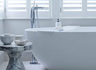 white bathroom ideas: white freestanding oval bath with white shutters