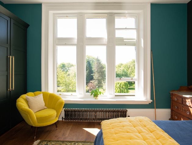 bedroom with bed yellow chair and large sash windows