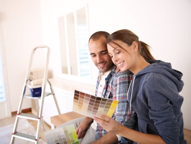 couple looking at paint colour charts as they decorate
