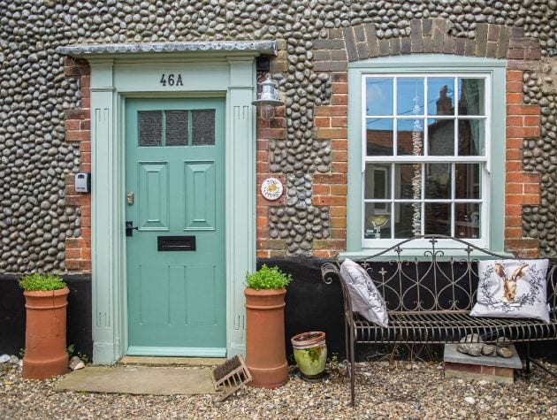 front of cottage with blue door sash window and stone cladding