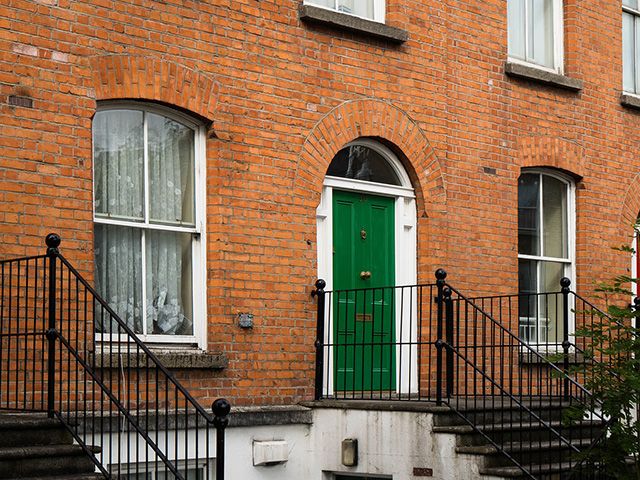green front door of brick house - green homes grant - goodhomesmagazine.com