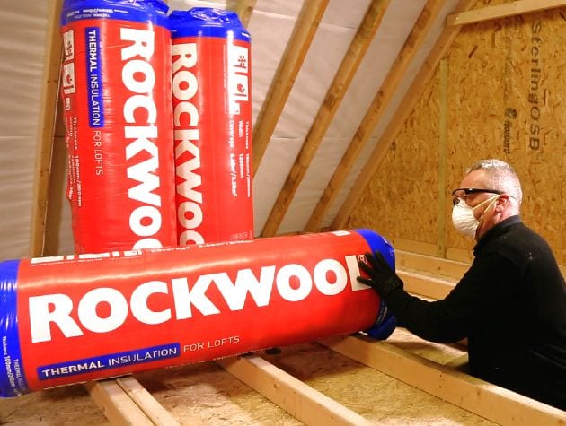 man in loft with rolls of rockwool insulation