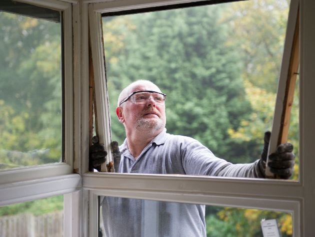 man with protective glasses repairing a window