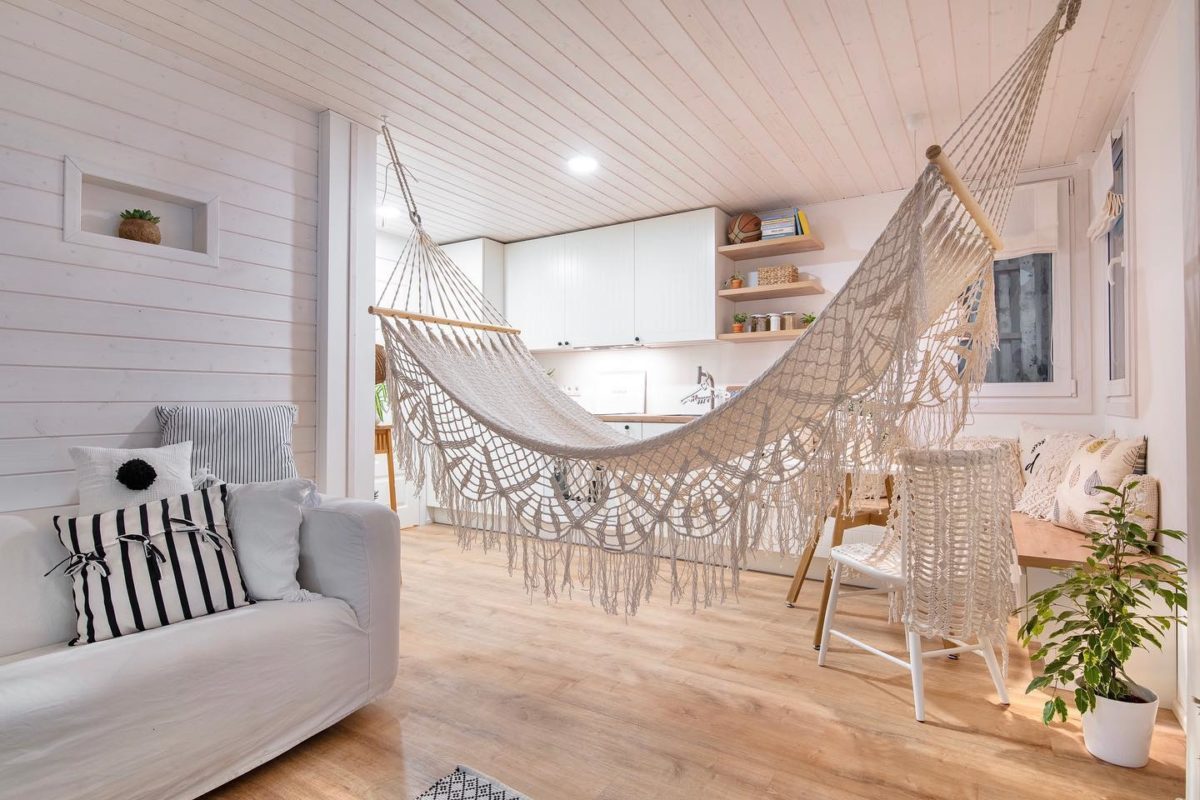 room with white timber walls, sofa and hammock suspended from ceiling