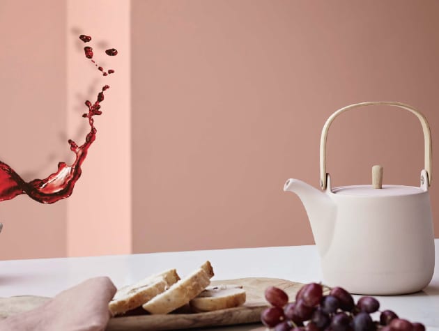 Teapot and food on a table against a pink wall