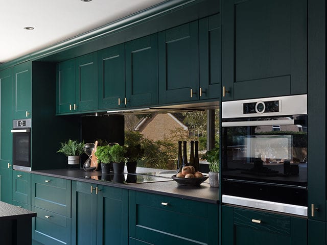 kitchen with dark green cabinets and two integrated ovens