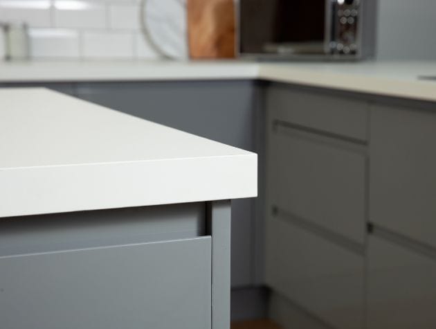 close up of a white kitchen worktop with grey doors