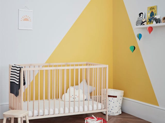 child’s bedroom with cot, toys and mustard triangles on white walls