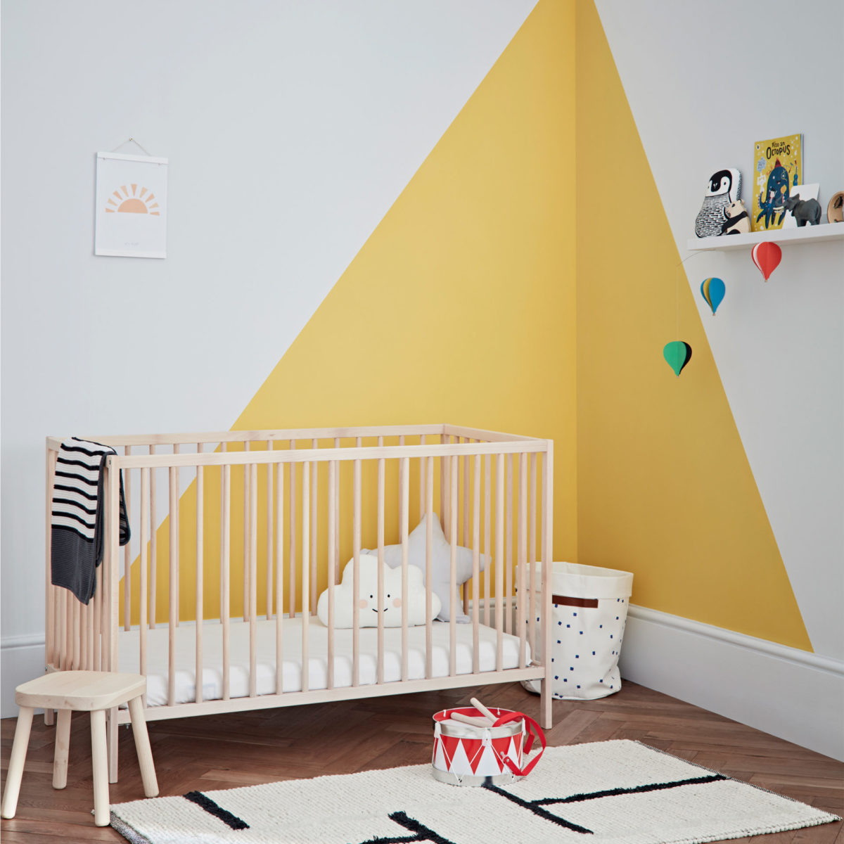 child’s bedroom with cot, toys and mustard triangles on white walls