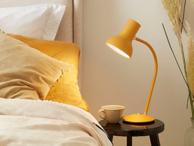 bedside table with drink and yellow anglepoise lamp