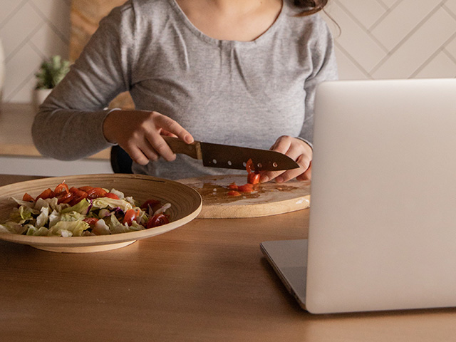 woman cooking in front of laptop