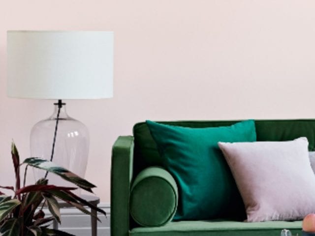 room with pink walls, green sofa, coffee table and pink chair