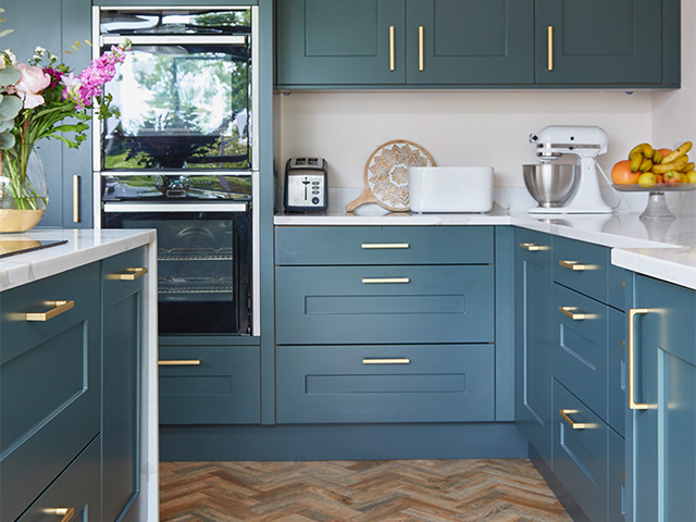 teal kitchen with gold handles and quartz worktop