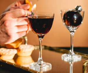 A Mince Pie Martini in a Nick & Nora glass topped with a flamed orange slice - christmas cocktails recipes - goodhomesmagazine.com