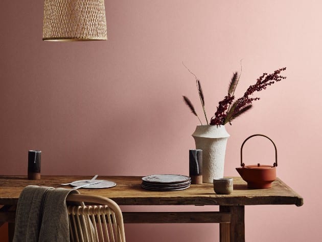 Wooden table and chair in front of a pink wall