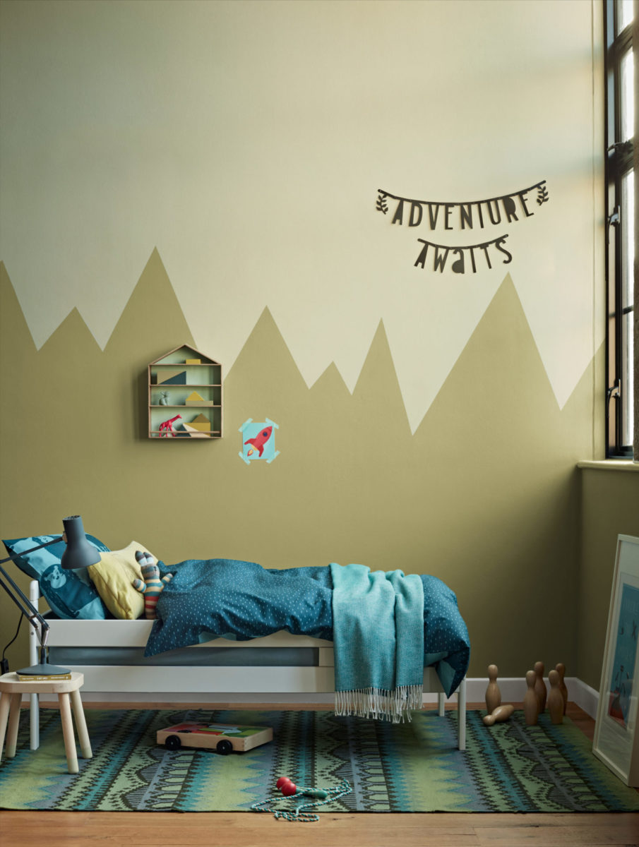 child’s bedroom with bed, rug and mountains painted on wall