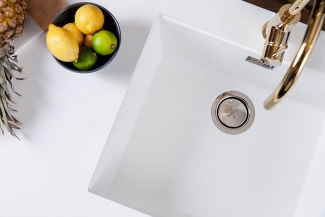 aerial view of white sink with brass/copper tap, next to fruit bowl