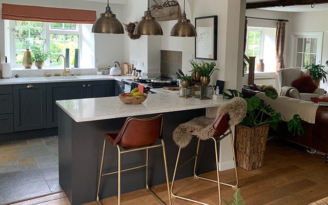 kitchen with grey cabinets and marble worktop, seats and pendant lighting