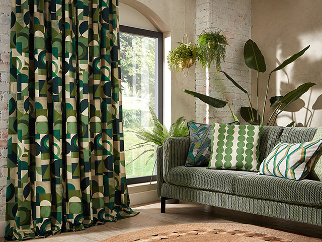 Bold curtains and geometric prints in green with green sofa and houseplants