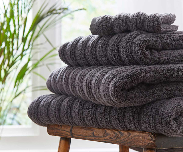 pile of grey bath towels - cosy bathrooms - goodhomesmagazine.com