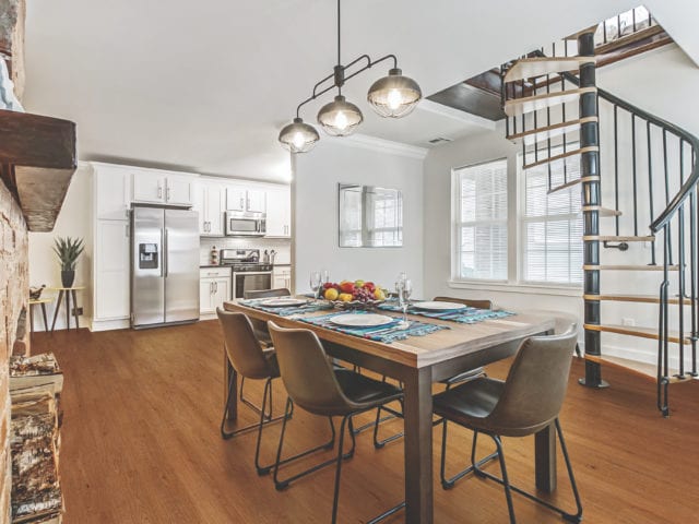 an open plan kitchen and dining area with table, chairs and spiral staircase