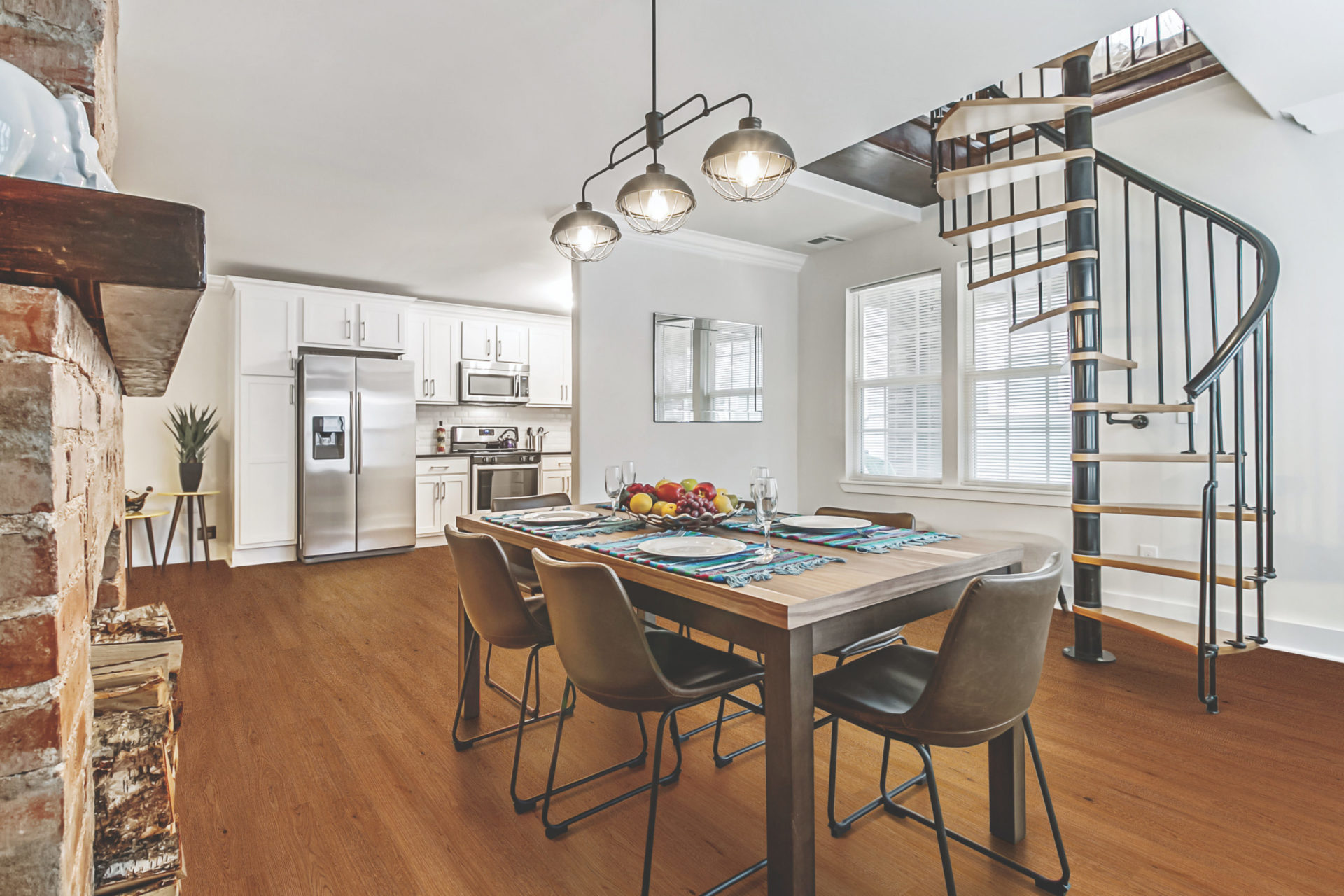 an open plan kitchen and dining area with table, chairs and spiral staircase