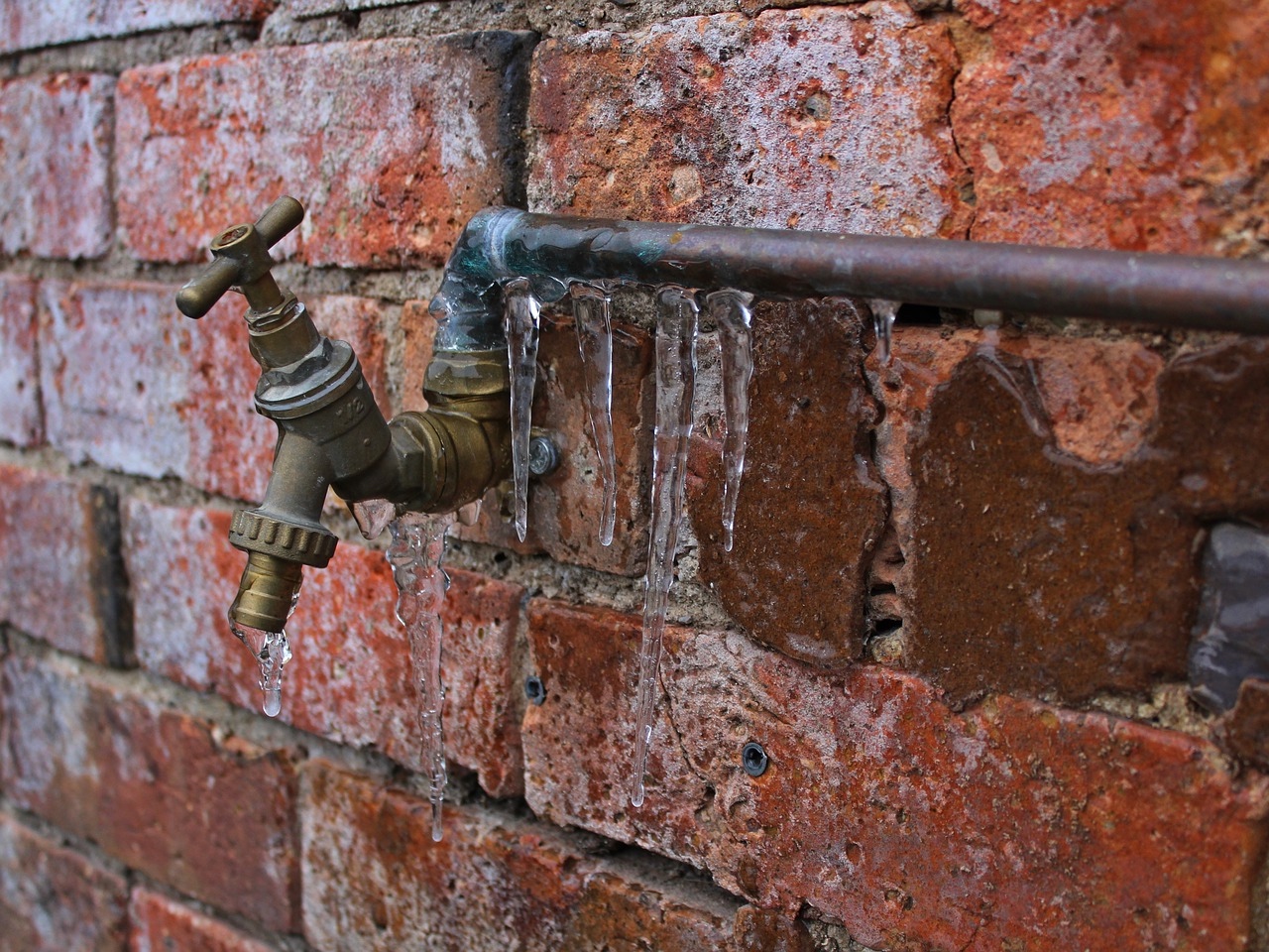 Frozen pipes outdoors on brickwork