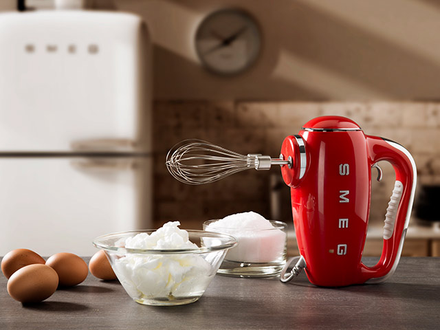 Red smeg hand mixer in kitchen with sugar in bowl and eggs