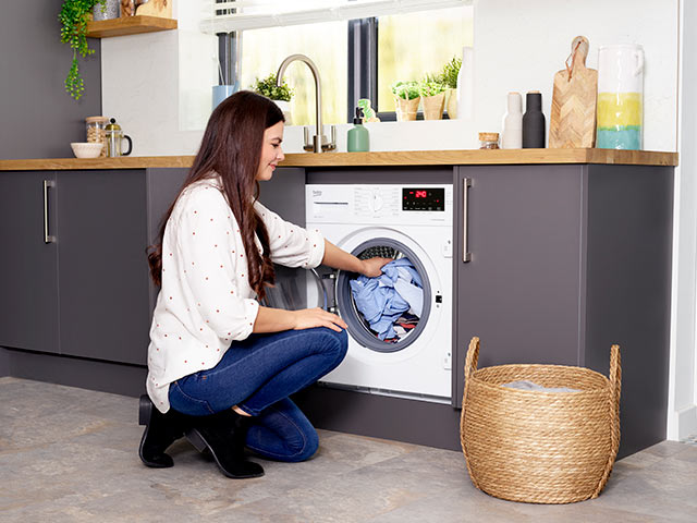 Woman loading washing machine from wicker laundry basket