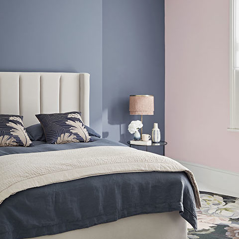 Bedroom with grey and pink walls, bed and night stand with pink lamp