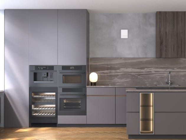 Contemporary dark grey handless kitchen with small white front panel of Blauberg Vento single room heat recovery ventilation unit in wall