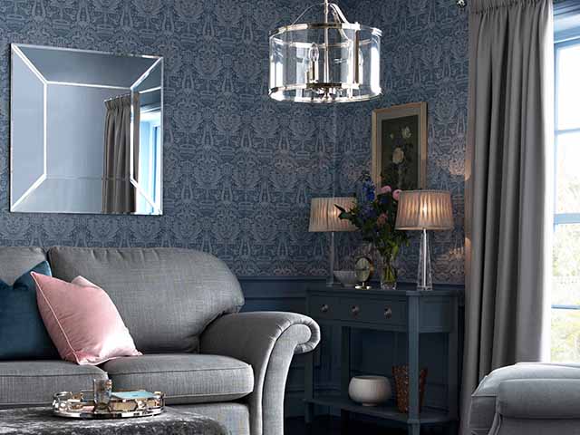 Navy wallpapered lounge with hanging ligjht, mirror and pink accessories, goodhomesmagazine.com