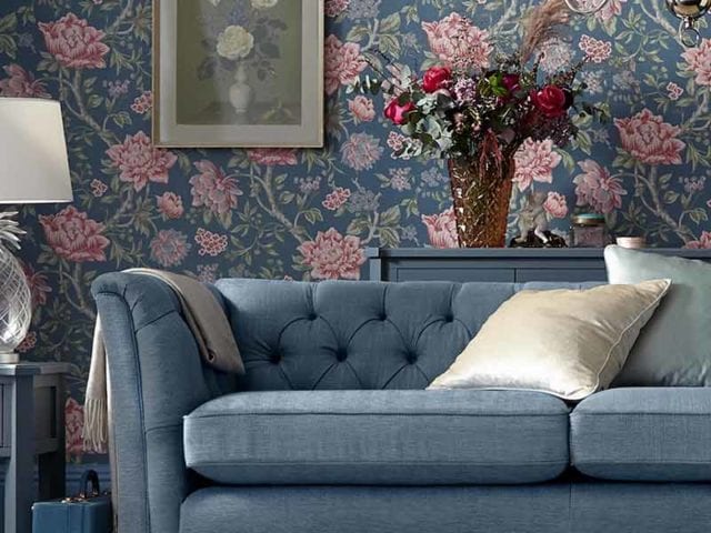 Floral wallpapered living room with naby pincushion sofa and bouquet in vase in background, goodhomesmagazine.com