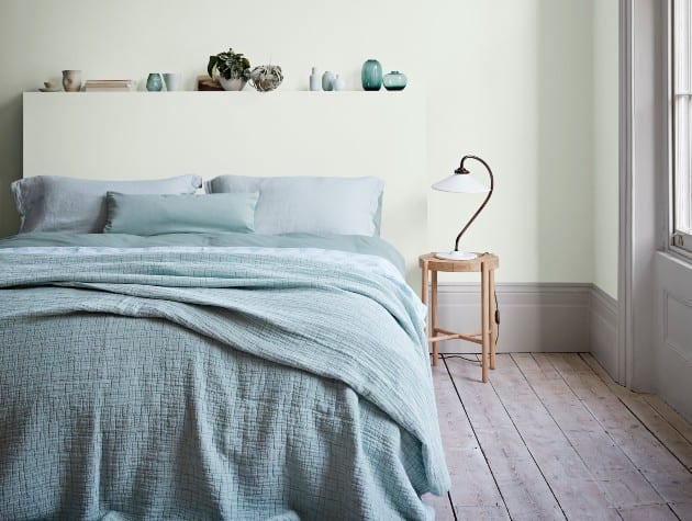contemporary bedroom with sage green walls, blue-green bed linen and wooden floor