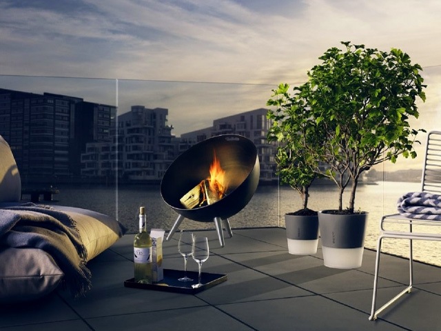 Black firepit globe with stainless steel legs on a balcony terrace by the river