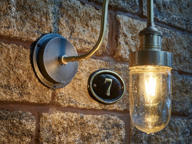 stone wall of home with exterior light and number 7 plaque