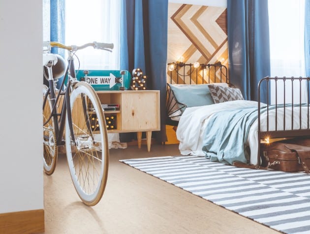 bedroom with single bed, rug, bicycle and cork floor