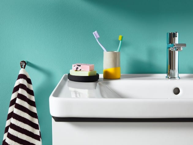 detail of white bathroom sink with soap, toothbrushes and towel