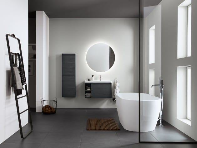 modern bathroom with freestanding bath, floating units and circular mirror