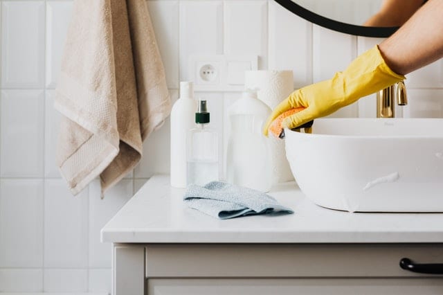 woman cleaning bathroom in rubber gloves