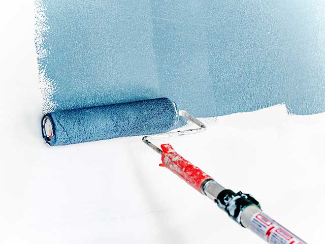 A roller brush painting in bright blue on a white wall - Goodhomesmagazine.com