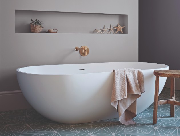 Interior of contemporary bathroom with mid-grey walls, teal geometric floor tiles and oval bath