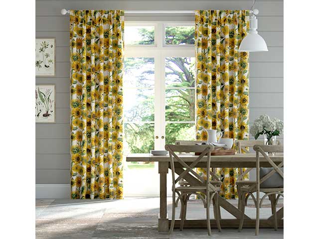 Yellow floor-length curtains with sunflower pattern behind a dining table - Goodhomesmagazine.com