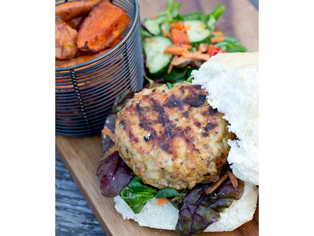 Turkey burger in a bun on a decorative wooden plank - Barbecue recipes - Goodhomesmagazine.com