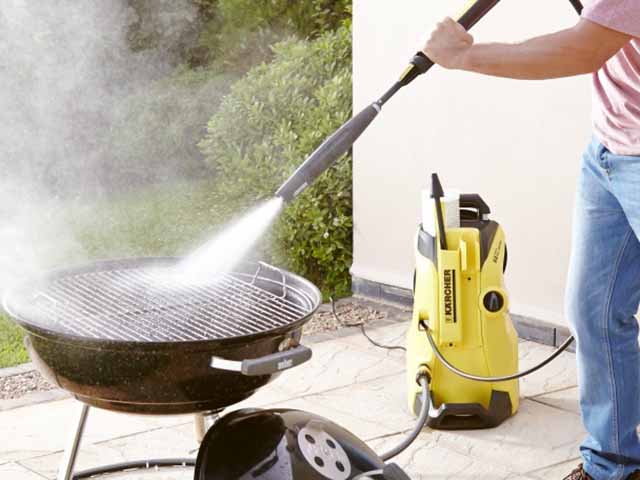 Man using a Kärcher pressure washer on a charcoal grill barbecue - Barbecue cleaning - Goodhomesmagazine.com