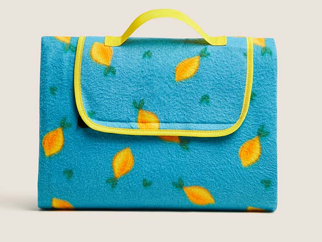 blue picnic blanket with lemons wrapped up on white isolated background - goodhomesmagazine.com