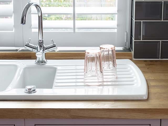 white kitchen sink with pink glasses on the draining board