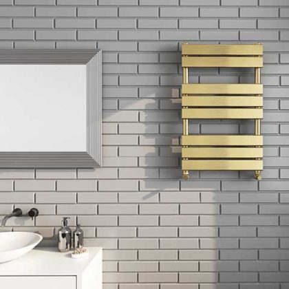 gold metal bathroom towel rail on pale grey tiled wall